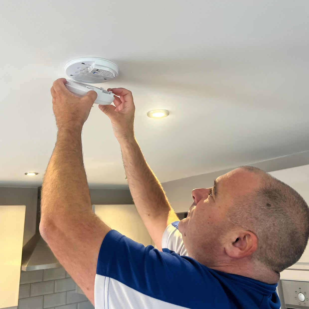 Smoke alarm installer fitting an alarm in a Derby property